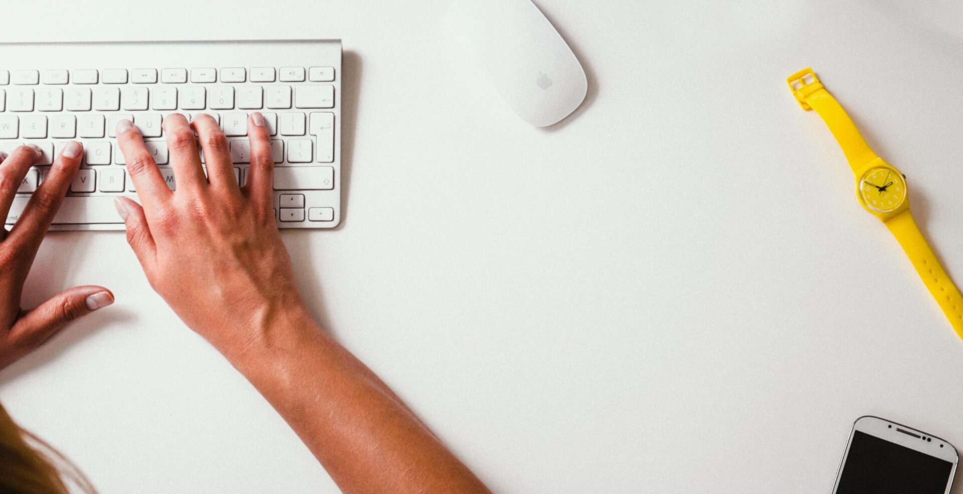 A person using a keyboard and mouse on a desk.